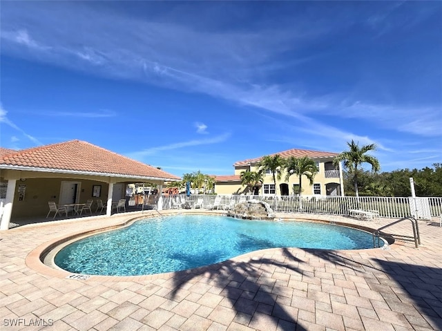 pool with a patio area and fence