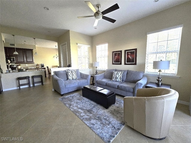 living room with light tile patterned floors, visible vents, baseboards, and a ceiling fan