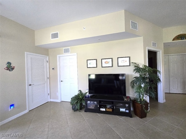 living room with tile patterned flooring, visible vents, and baseboards