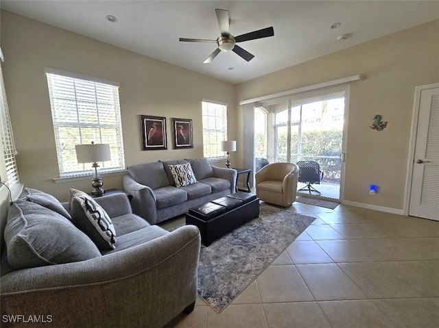 living room featuring a ceiling fan, baseboards, and light tile patterned floors