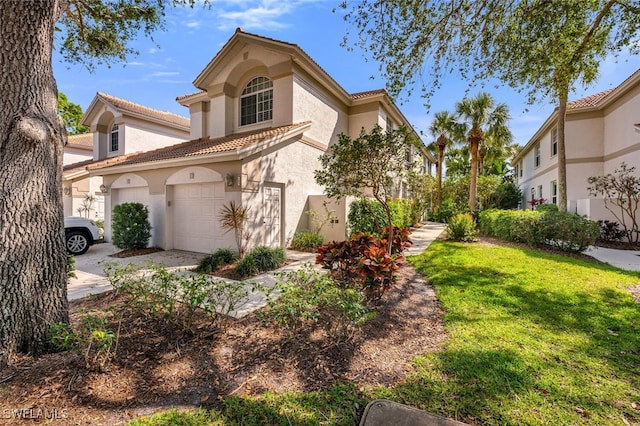 mediterranean / spanish-style house featuring a tile roof, a front yard, concrete driveway, and stucco siding