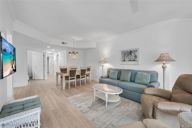 living room with baseboards, visible vents, ornamental molding, light wood-type flooring, and a chandelier