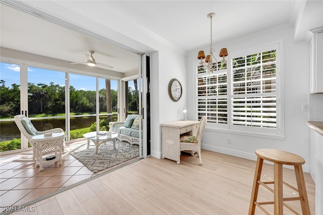 sunroom / solarium featuring a water view and ceiling fan with notable chandelier