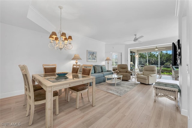 dining room featuring light wood-style flooring, baseboards, crown molding, and ceiling fan with notable chandelier