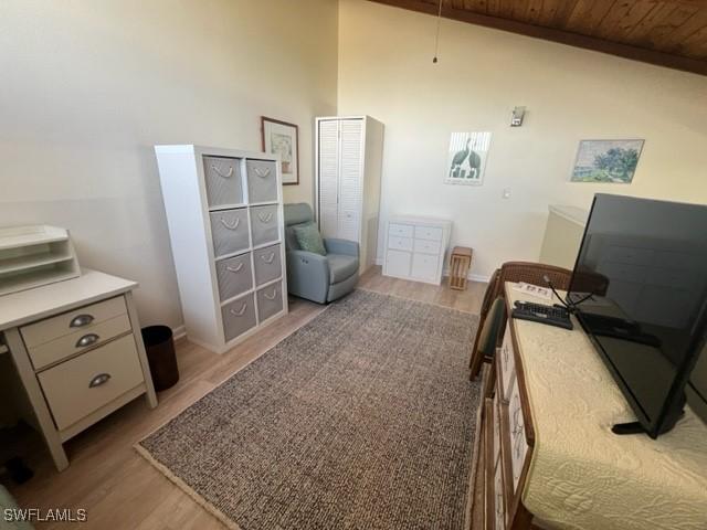 bedroom with light wood-type flooring, wooden ceiling, baseboards, and high vaulted ceiling