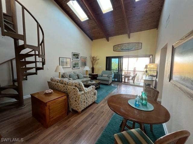 living area with a skylight, stairway, wood finished floors, high vaulted ceiling, and wooden ceiling