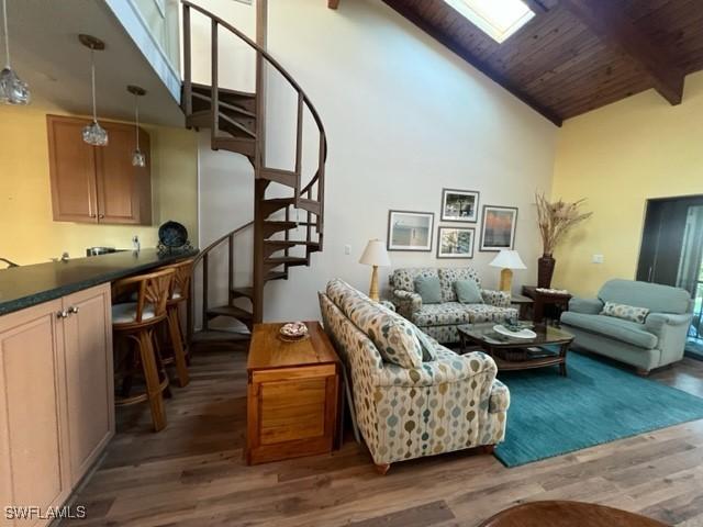 living room featuring wooden ceiling, dark wood-style flooring, a skylight, stairway, and beamed ceiling