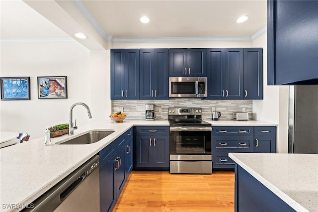 kitchen with crown molding, appliances with stainless steel finishes, a sink, blue cabinets, and light wood-type flooring