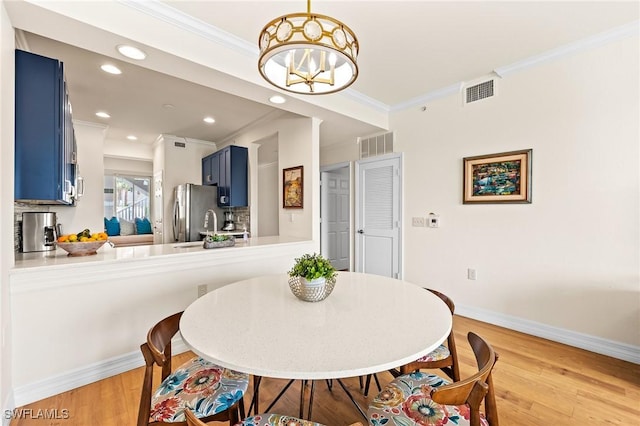 dining area featuring baseboards, visible vents, crown molding, and light wood finished floors