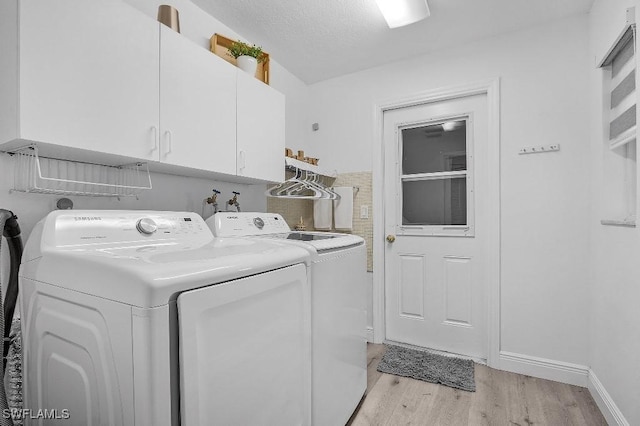 washroom featuring a textured ceiling, light wood-style floors, cabinet space, and washer and dryer