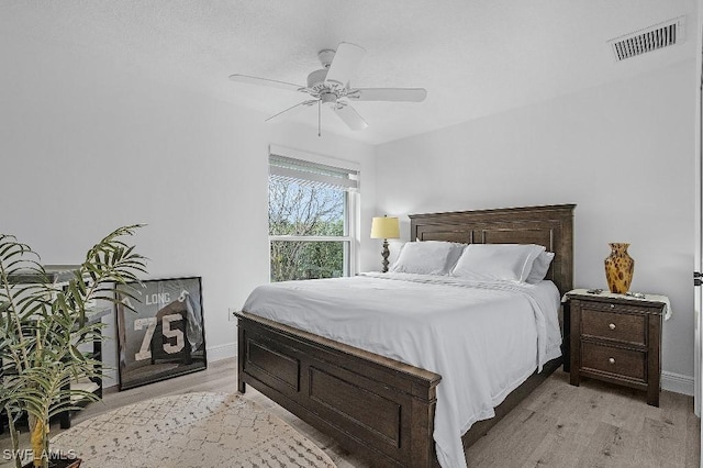 bedroom featuring a ceiling fan, light wood-type flooring, visible vents, and baseboards