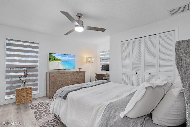 bedroom featuring ceiling fan, a closet, visible vents, and light wood-style floors