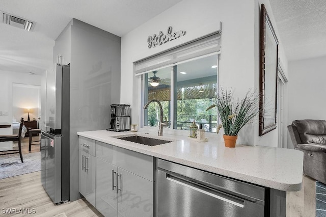 kitchen with stainless steel appliances, visible vents, light wood-style flooring, open floor plan, and a sink