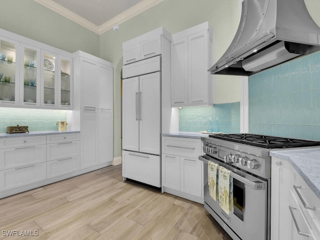 7627 Palmer Ct, Naples, FL 34113 - kitchen with crown molding, wall chimney exhaust hood, light wood-type flooring, white cabinetry, and premium appliances