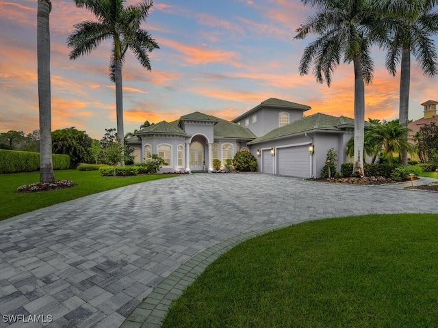 7627 Palmer Ct, Naples, FL 34113 - mediterranean / spanish-style house featuring a lawn, a garage, stucco siding, and decorative driveway