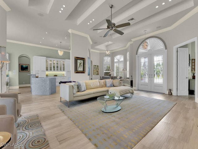 living room with light wood-style floors, recessed lighting, french doors, and a towering ceiling