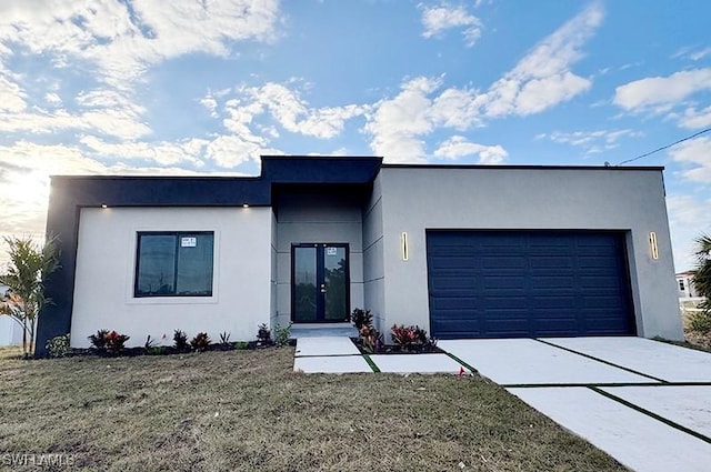 view of front of house with a front yard, concrete driveway, an attached garage, and stucco siding