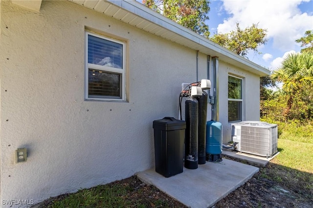 view of home's exterior with stucco siding and central AC unit