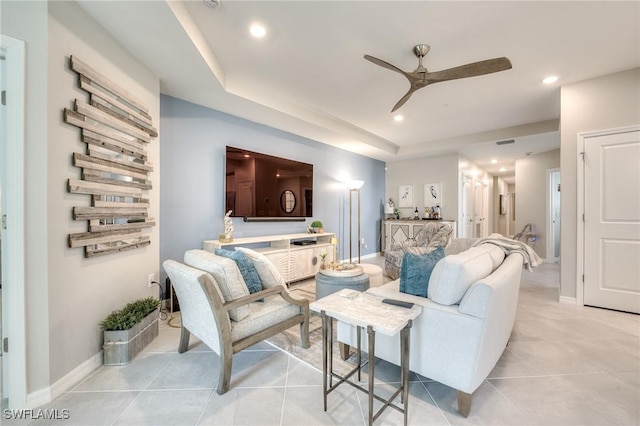 living room featuring light tile patterned flooring, recessed lighting, a ceiling fan, baseboards, and a raised ceiling