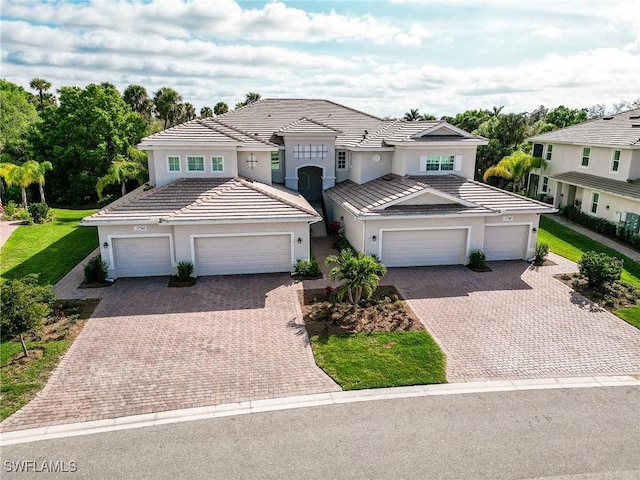 view of front of property with an attached garage, a tile roof, and decorative driveway