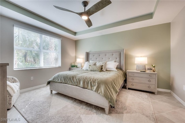 bedroom with light tile patterned floors, ceiling fan, a raised ceiling, and baseboards