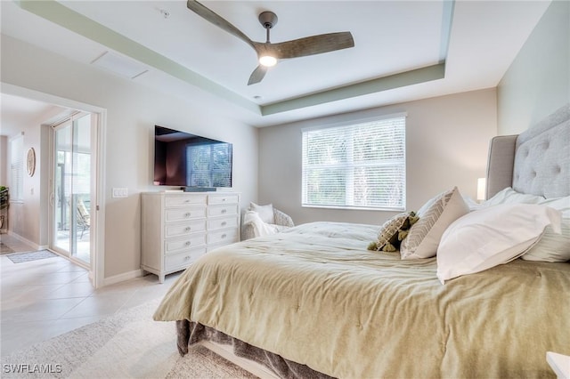 bedroom featuring access to exterior, a tray ceiling, light tile patterned flooring, ceiling fan, and baseboards