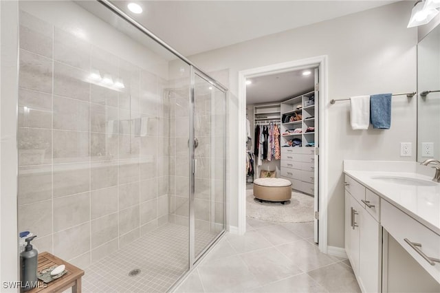 bathroom featuring a spacious closet, a stall shower, tile patterned flooring, and vanity