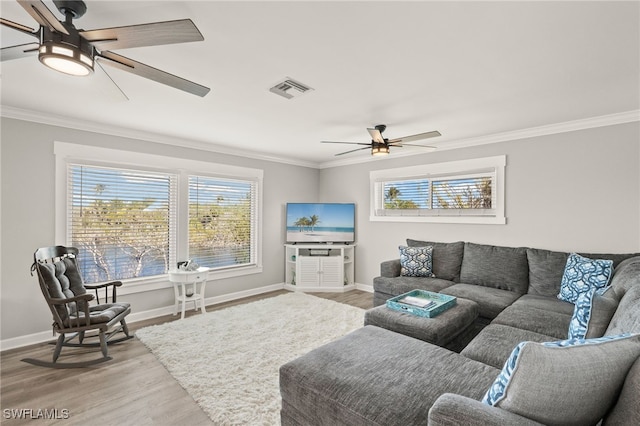 living area with visible vents, plenty of natural light, crown molding, and a ceiling fan