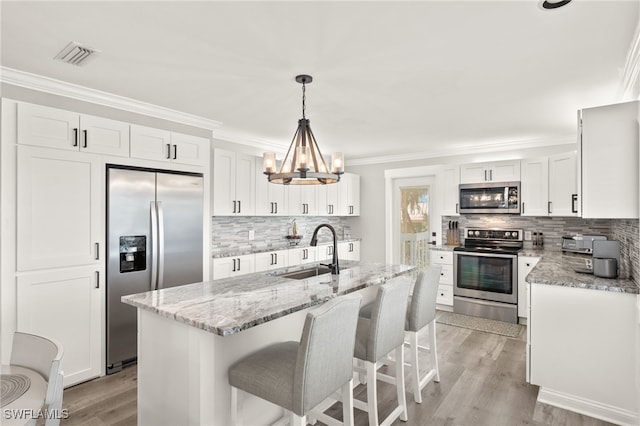 kitchen with visible vents, crown molding, a notable chandelier, stainless steel appliances, and a sink