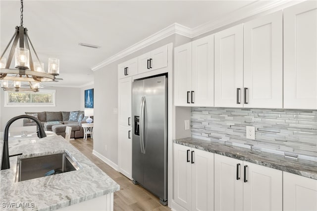 kitchen featuring white cabinets, ornamental molding, stainless steel fridge with ice dispenser, and a sink