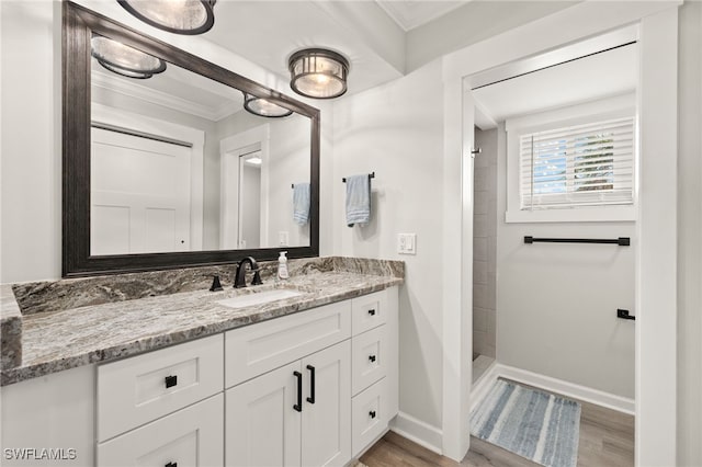 bathroom with a stall shower, vanity, crown molding, and wood finished floors