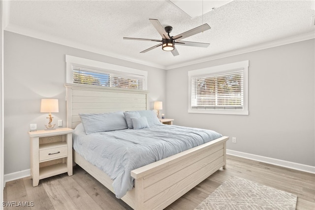 bedroom featuring multiple windows, a textured ceiling, light wood-style flooring, and ornamental molding