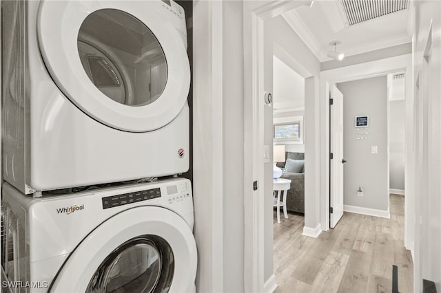 laundry room with visible vents, stacked washing maching and dryer, laundry area, ornamental molding, and light wood-style floors