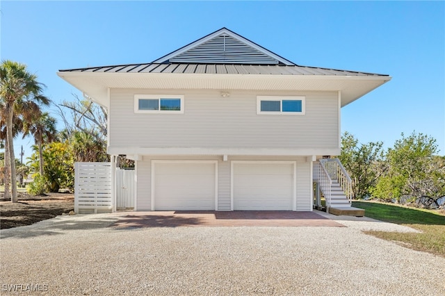 exterior space with stairway, a garage, driveway, and metal roof