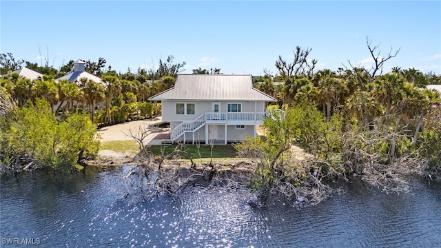 back of house featuring stairway, metal roof, and a water view