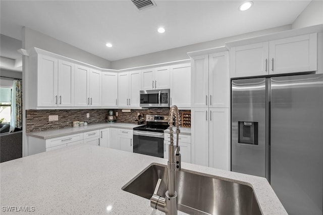 kitchen with visible vents, backsplash, appliances with stainless steel finishes, white cabinets, and a sink