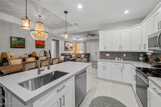 kitchen with appliances with stainless steel finishes, pendant lighting, white cabinets, and a sink