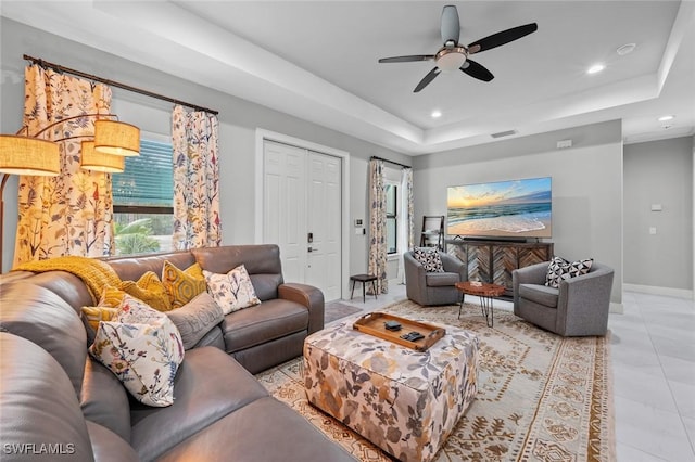 living area with light tile patterned floors, baseboards, a ceiling fan, a tray ceiling, and recessed lighting