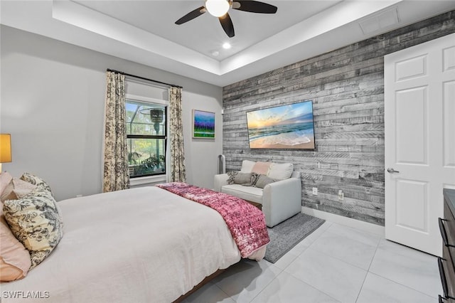 bedroom with a tray ceiling, recessed lighting, an accent wall, light tile patterned flooring, and baseboards