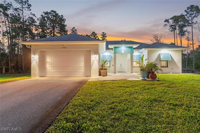 view of front of property featuring driveway, a garage, a front lawn, and stucco siding