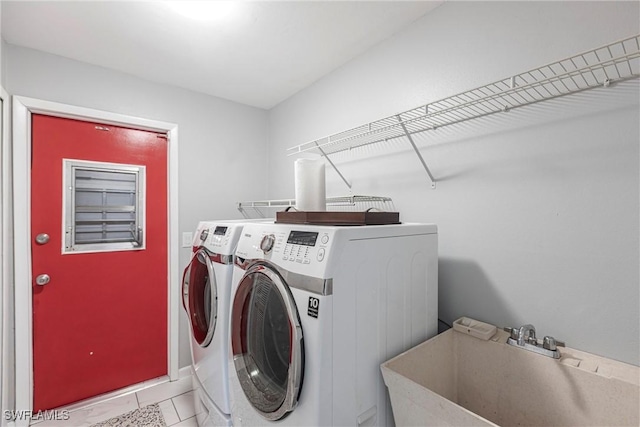 clothes washing area featuring washer and dryer, laundry area, a sink, and tile patterned floors