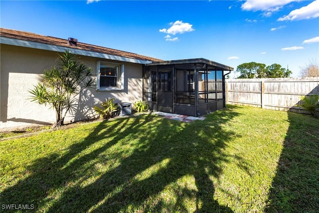 rear view of house featuring a sunroom, fence, a lawn, and stucco siding