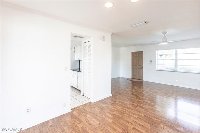 unfurnished room featuring wood finished floors, visible vents, a ceiling fan, baseboards, and crown molding