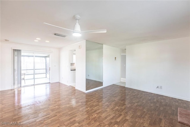 spare room featuring visible vents, ceiling fan, baseboards, and wood finished floors