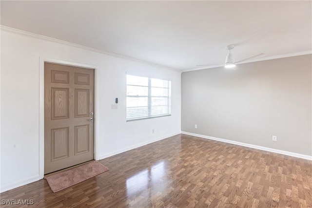 spare room with baseboards, wood finished floors, and crown molding