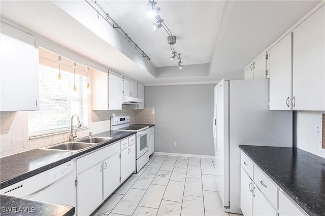 kitchen with white appliances, marble finish floor, a tray ceiling, under cabinet range hood, and a sink