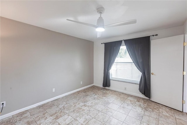 spare room featuring ceiling fan and baseboards