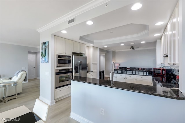 kitchen with stainless steel appliances, visible vents, white cabinetry, dark stone counters, and a peninsula