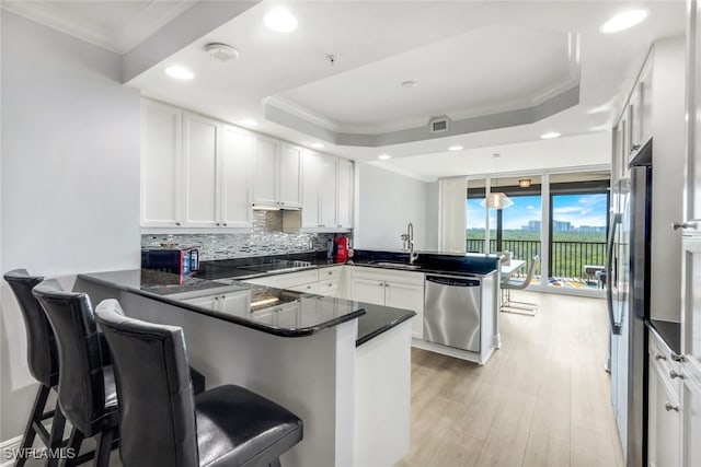 kitchen with stainless steel appliances, a breakfast bar, white cabinetry, and a peninsula