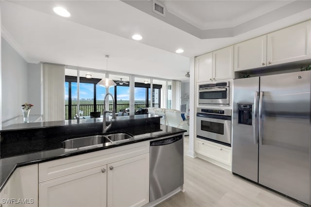 kitchen featuring ornamental molding, hanging light fixtures, appliances with stainless steel finishes, and white cabinetry